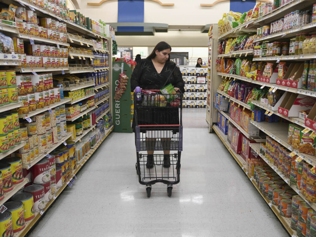 Jaqueline Benitez pushes her cart down an aisle as she shops for groceries at a supermarket in Bellflower, Calif., on Monday, Feb. 13, 2023. Benitez, 21, who works as a preschool teacher, depends on California’s SNAP benefits to help pay for food. A woman shopping in a supermarket