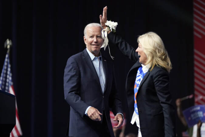 First Lady Jill Biden waves to the crowd as President Joe Biden stands behind her.