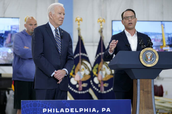 President Biden listens as Gov. Shapiro speaks at a podium.