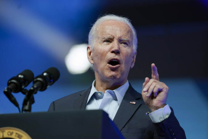 An up-close view of Biden speaking at a podium as he gestures.