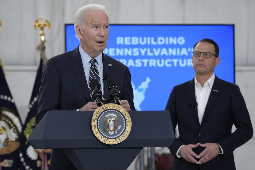 Biden speaks at a podium as Shapiro looks on.