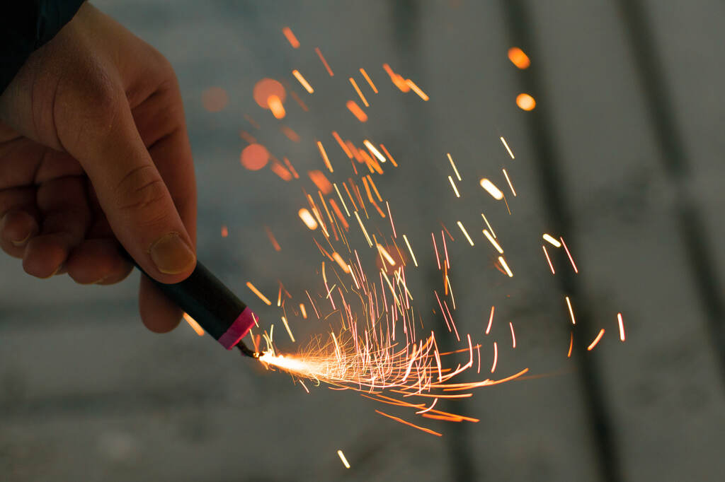 Burning Firecracker With Sparks. Guy Holding A Petard In A Hand. Man holds a burning firecracker
