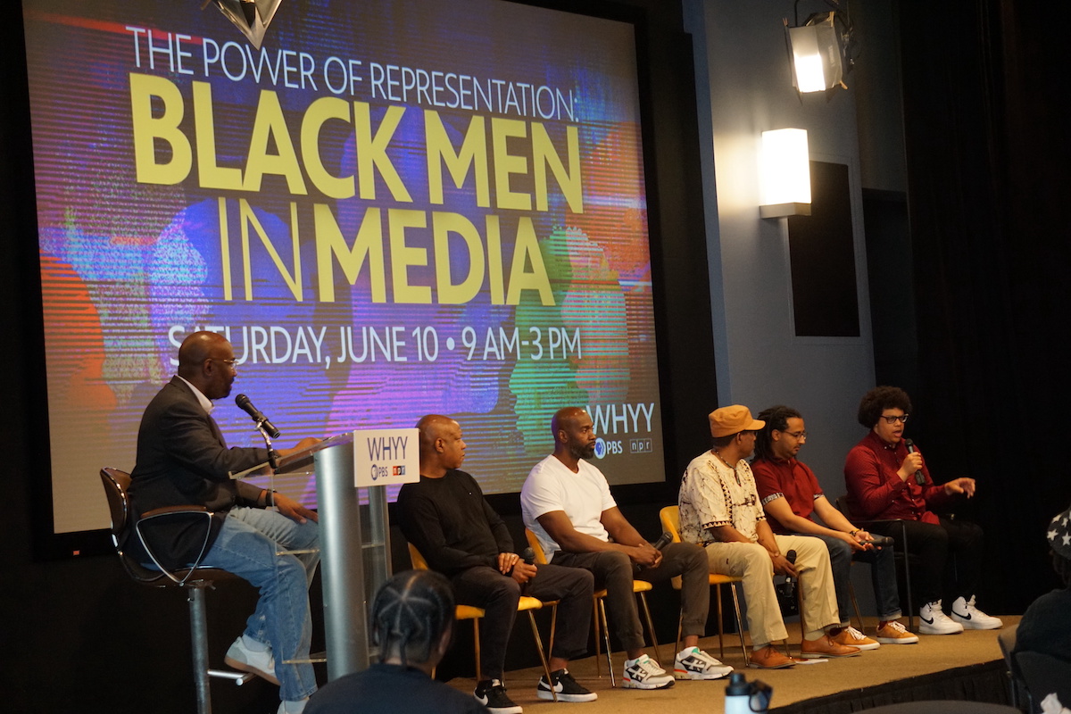 black-men-in-media-5 P. Kenneth Burns is seated at a podium, turned towards panelists who are seated onstage.