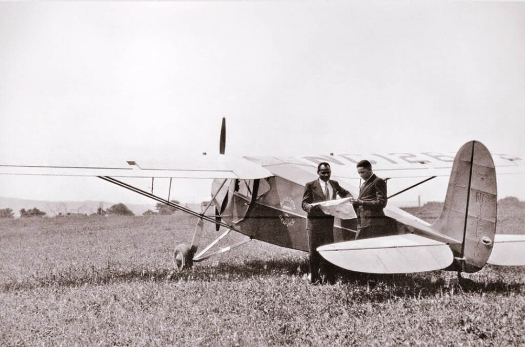 blackaviators-forsythe-anderson-02 A black and white photo shows C. Alfred Anderson and Albert E. Forsythe next to an airplane.
