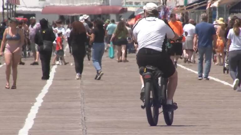 A man riding an e-bike on the boardwalk.