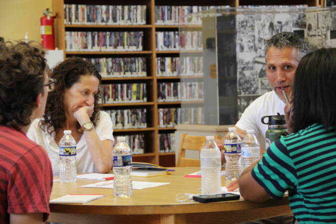 People talk to one another while seated around a table.