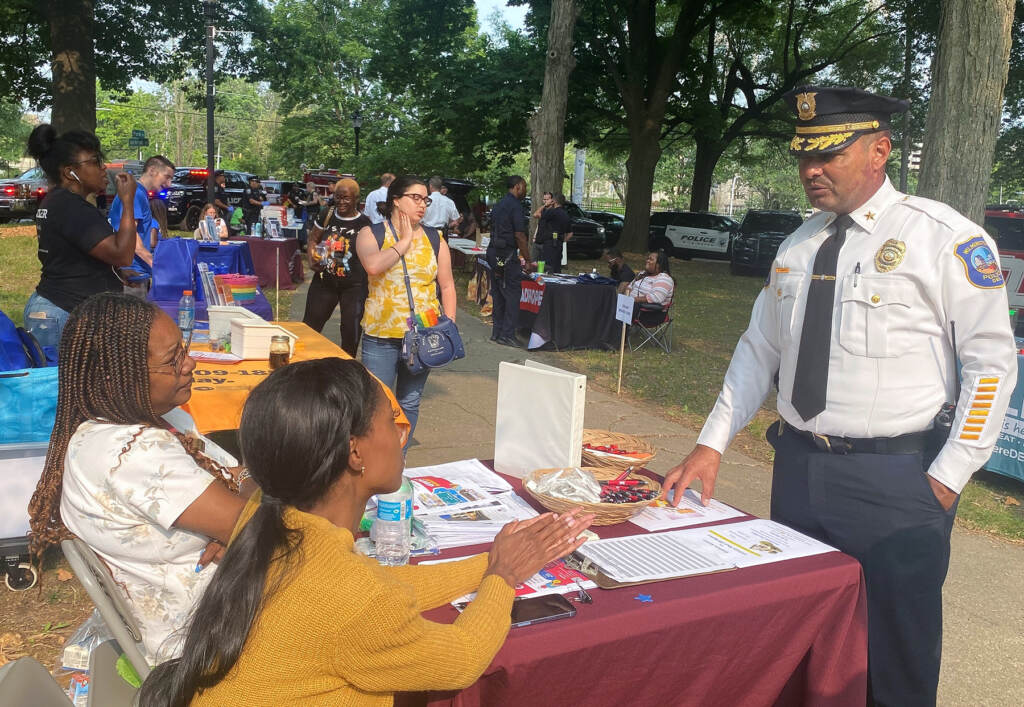 campos-and-skeptics-c-ransom-2023-06-28 Chief Campos speaking with 2 women sitting at a desk at the fair.