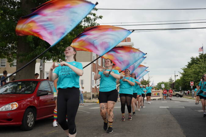 Main Line Independent members twirl flags in front of spectators