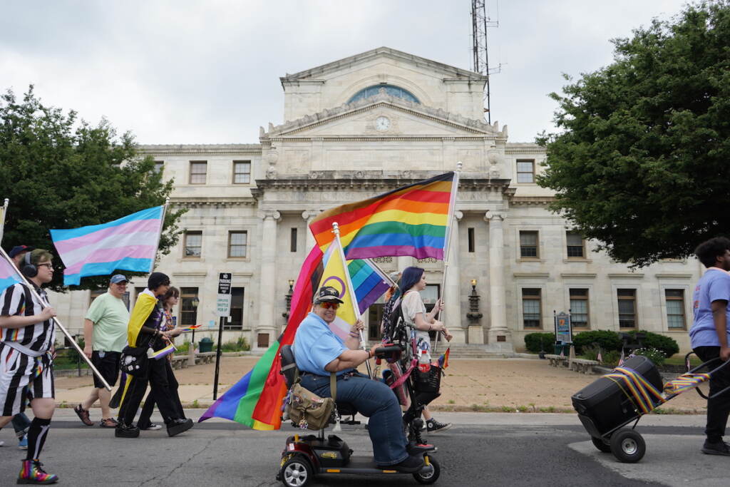 delco-pride-parade-9 Pride participants pass in front of the Delaware County Courthouse, holding Pride flags.