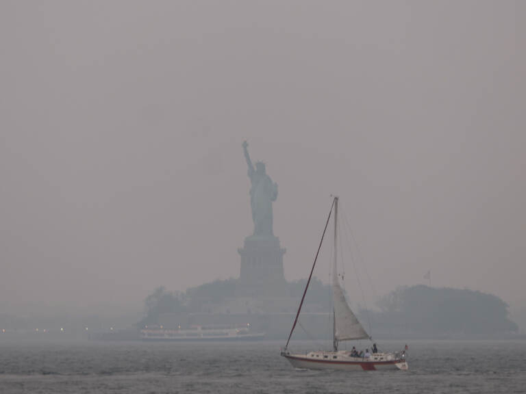 The Statue of Liberty stands shrouded in a reddish haze as a result of Canadian wildfires