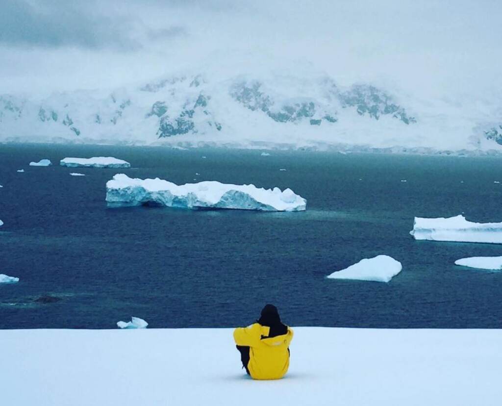 lawrence-phillips-antarctica-2 Lawrence Phillips sitting and looking out on the ocean and icebergs.