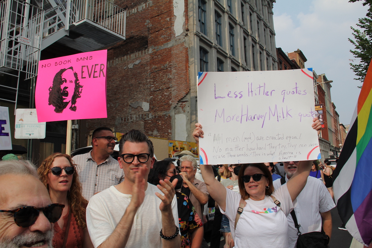 People hold up signs in protest of Moms for Liberty.