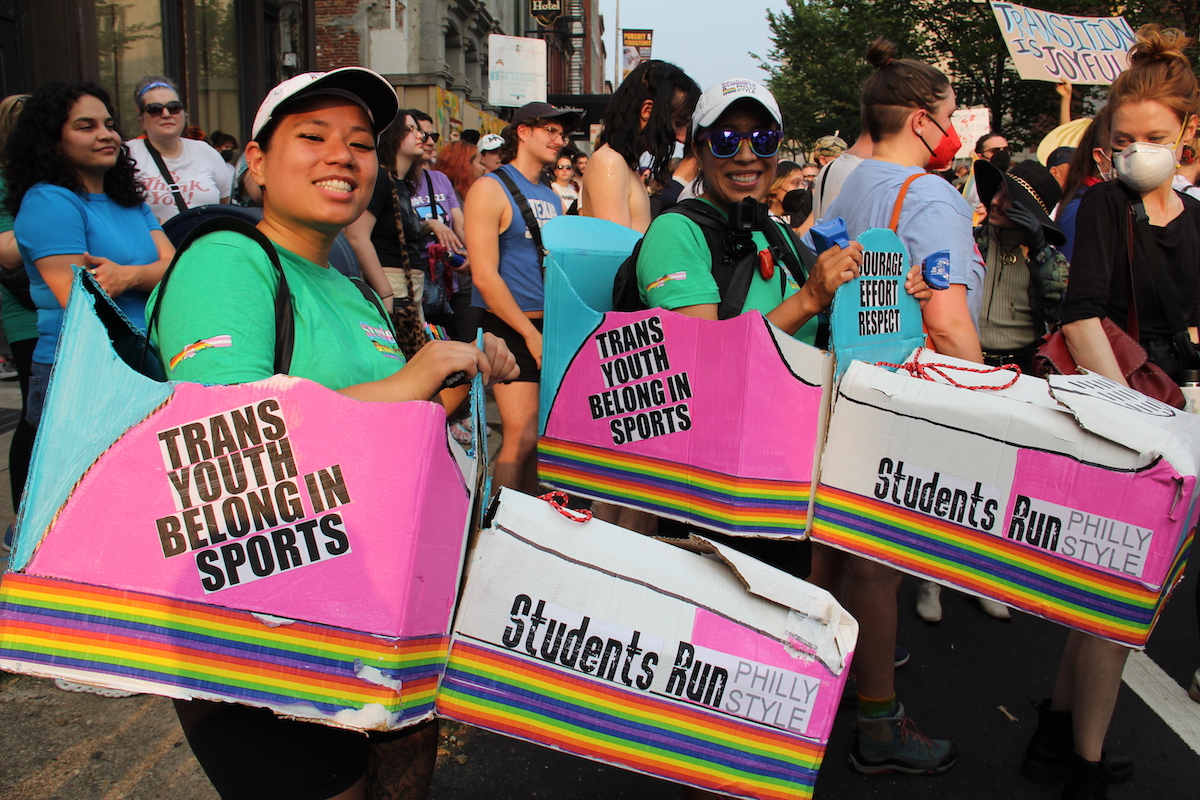 Kim Kim (left) and CC Tellez (right) participate in a protest against Moms for Liberty. Both carry signs that read 