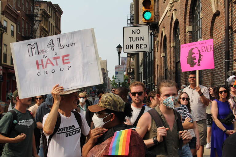 People hold up signs protest Moms for Liberty.
