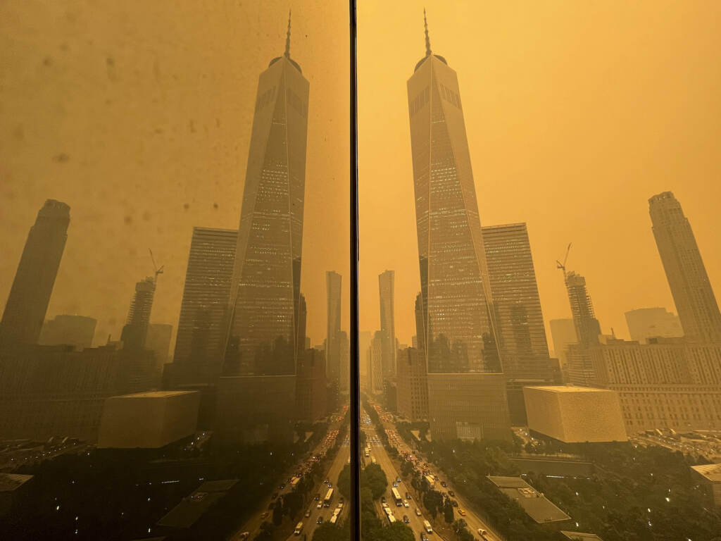 Traffic moves along West Street past One World Trade Center, in this mirror image reflected in the facade of a building