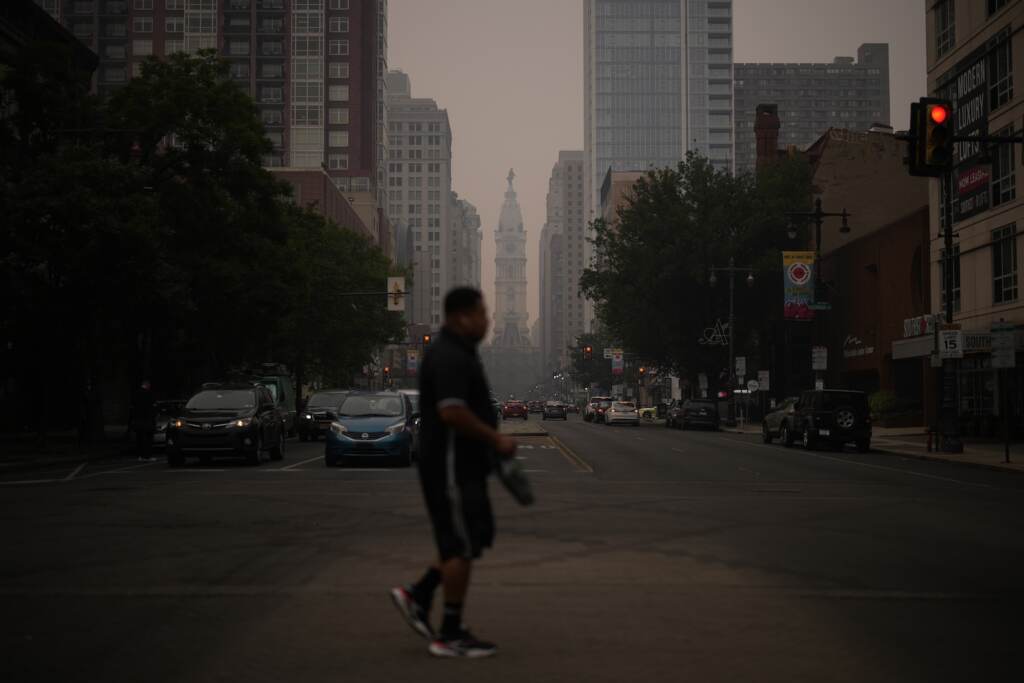 philadelphia-center-city-haze-wildfire-smoke-AP-060923 A man crossing the street, with a very hazy sky
