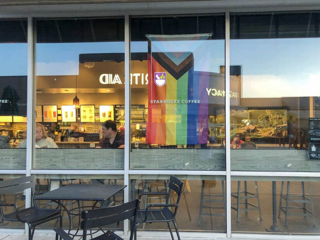 A Pride flag hangs in the window of a Starbucks store.