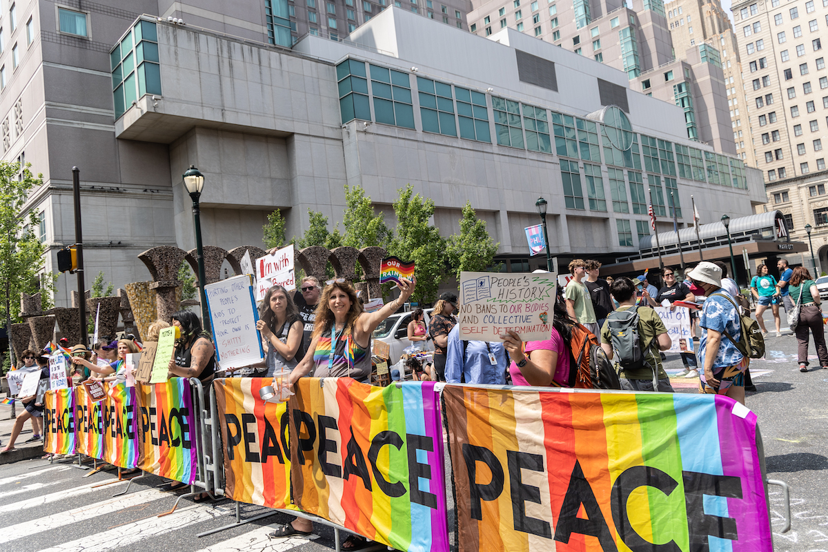 Protesters hold banners that are rainbow-colored with the word 