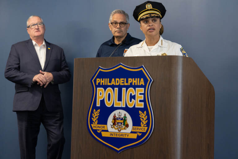 Commissioner Danielle Outlaw speaks at a podium. Mayor Jim Kenney and DA Larry Krasner look on behind her.