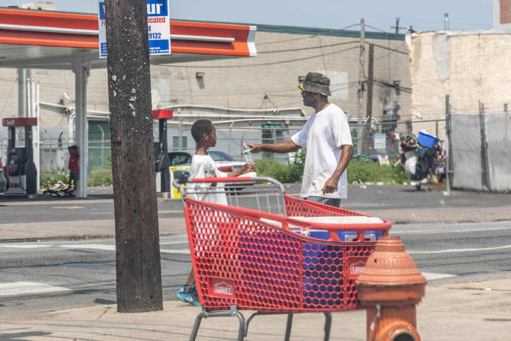 Two people sell water to passing cars.
