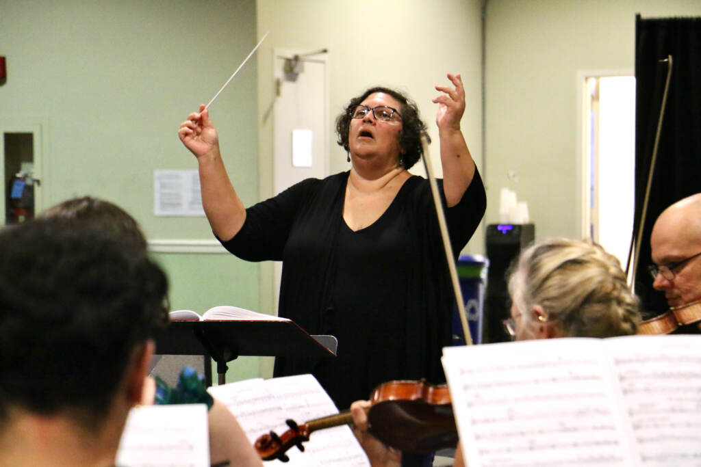 Elizabeth Braden lifts her arms up as she conducts musicians and singers for Opera Philadelphia.