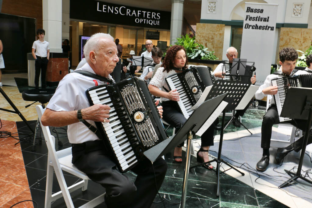 2023 07 13-e lee-frank busso sr christina busso-king of prussia mall-american accordionists association Frank Busso Sr. (left), of Woodbridge, Va., raised an accordion playing family, His son, daughter, and grandchildren joined him for a performance at King of Prussia Mall during the annual American Accordionists' Association convention. (Emma Lee/WHYY)