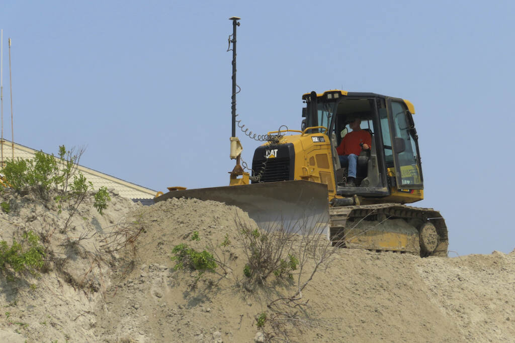 Defiant Beach Town A bulldozer reshapes a sand dune
