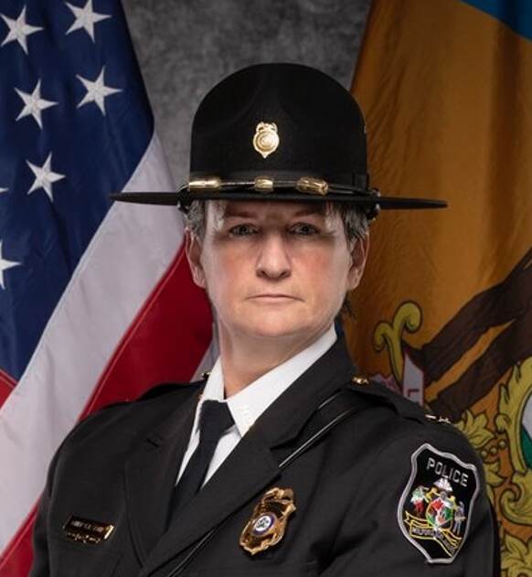 Ashe_Cecilia_2023 Milford Police Chief Cecilia Ashe poses for a photo in uniform with a U.S. flag in the background.