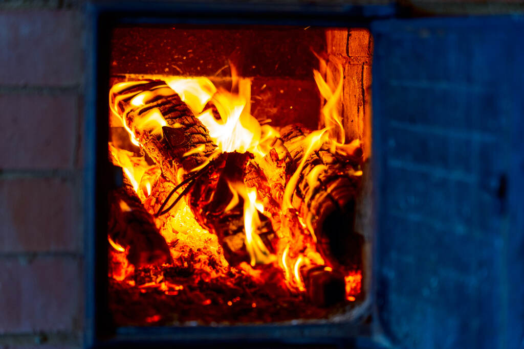 Open Door Of Wood-burning Stove, Opens And Throws Firewood In The Wood Stove With Gloves, A Burning Open Door Of Wood-burning Stove