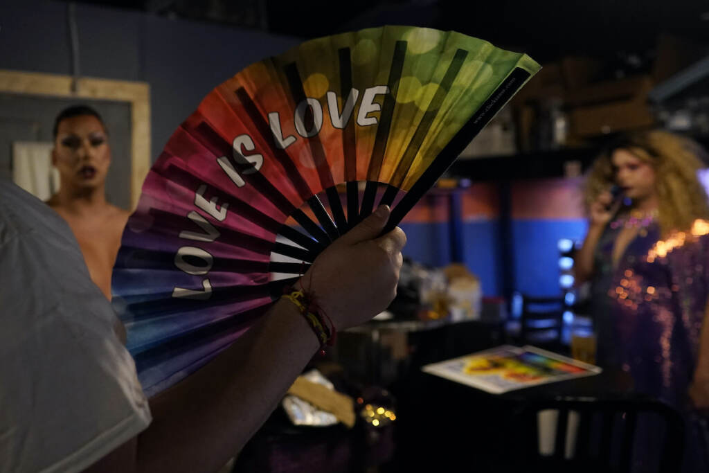 Ryan Geiger holds a rainbow "Love is Love" fan