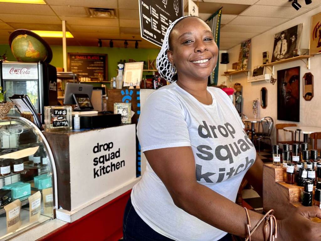 Abundance Child Xi-El smiles, posing for a photo inside her restaurant, Drop Squad Kitchen.