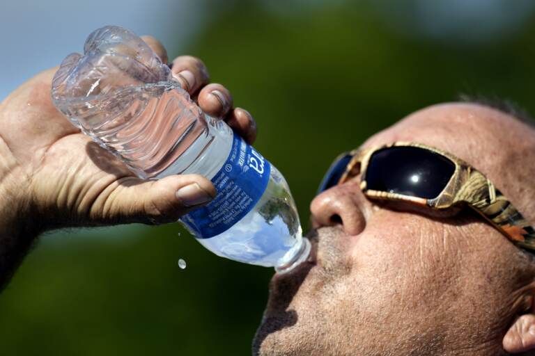 Robert Harris drinks water while taking a break from digging fence post holes, Tuesday, June 27, 2023, in Houston.