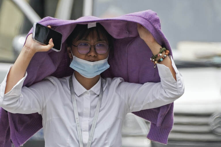 A woman shelters herself from the intense sun with a sweater.
