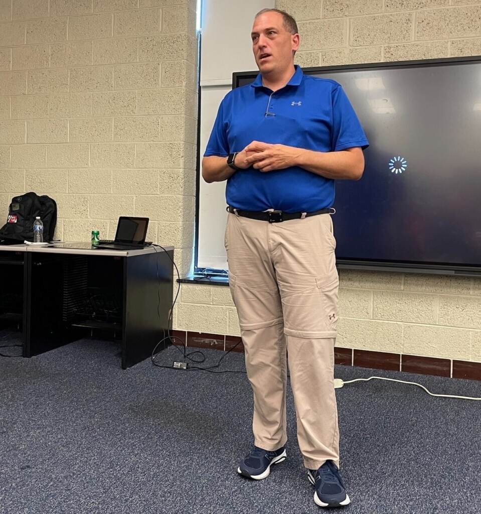 A.J. Schall speaks at the front of a room.