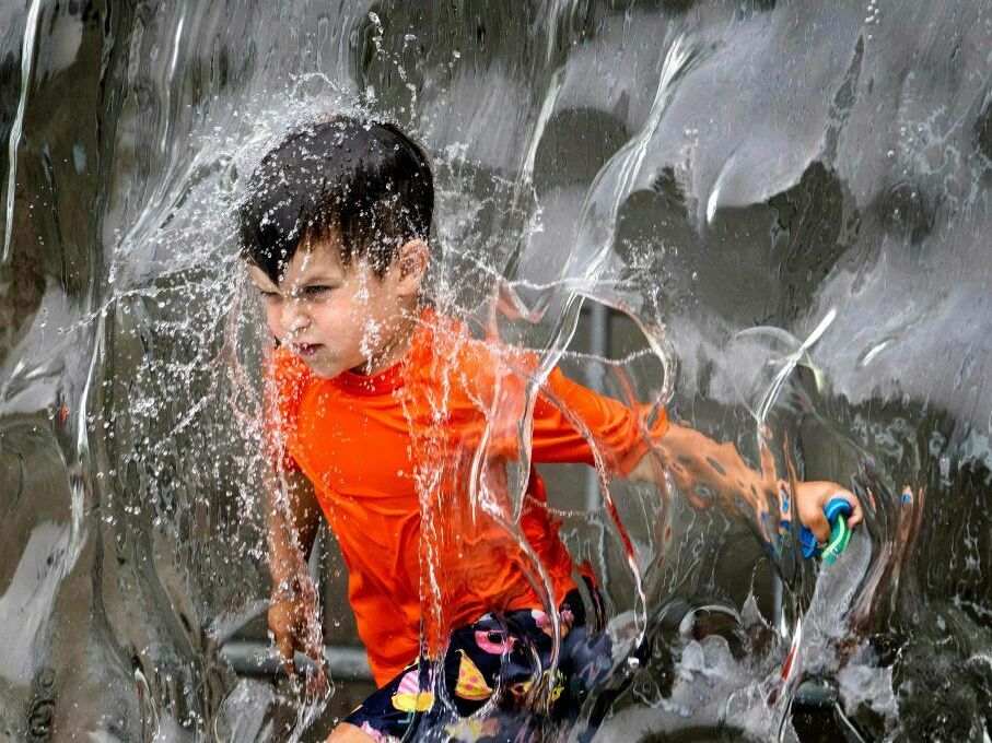 A young boy plays in the water fountain at Yards Park in Washington, DC