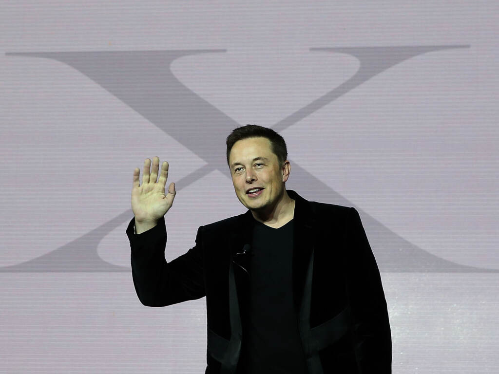 Tesla CEO Elon Musk speaks during an event to launch the new Tesla Model X Crossover SUV on Sept. 2015 in Fremont, California. The billionaire has a long-time affinity for the letter “X.” Elon Musk gestures while standing in front of a giant letter 'X'