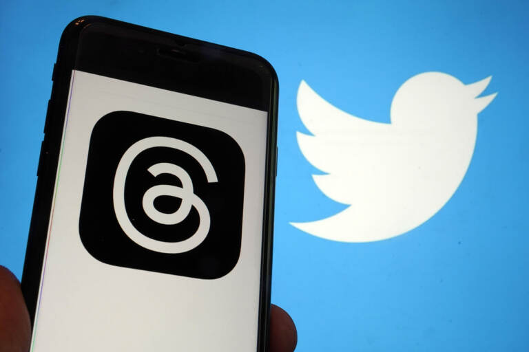 The logo for Meta's new app Threads is shown in the foreground. In the background is the logo for Twitter.