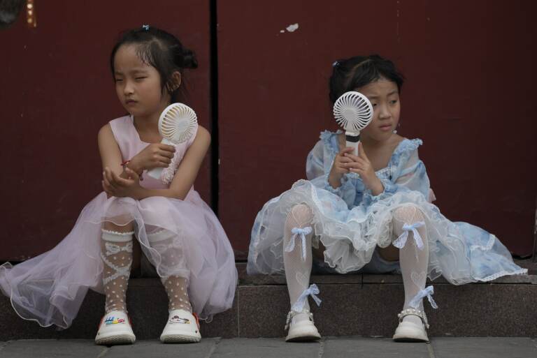 Children cool themselves with fans.