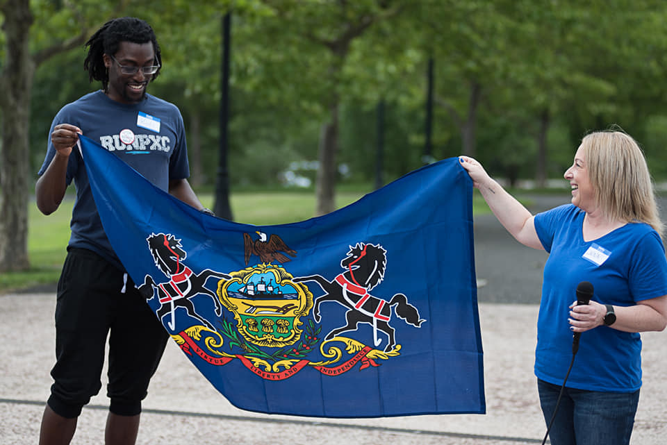nope-lawsuit-2 Kofi Osei and Jenn Foster hold a flag together.