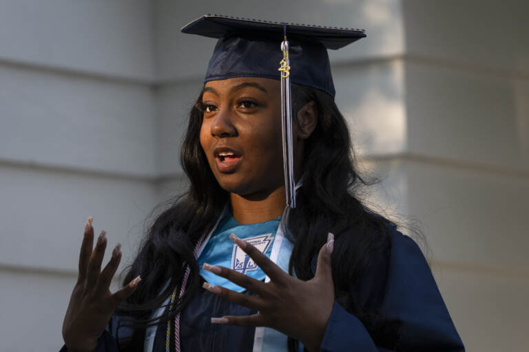 Nylla Miller speaks in a close-up photo. She is wearing her high school graduation cap and gown.