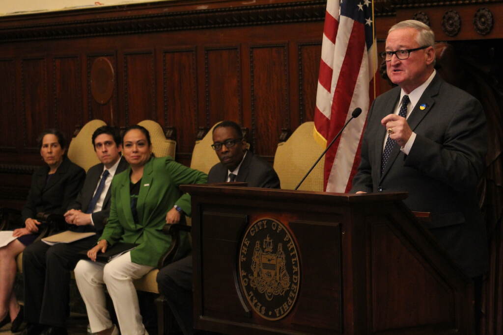 philadelphia-ghost-gun-litigation-5 Mayor Jim Kenney speaks into a microphone at a podium at City Hall while other city officials look on.