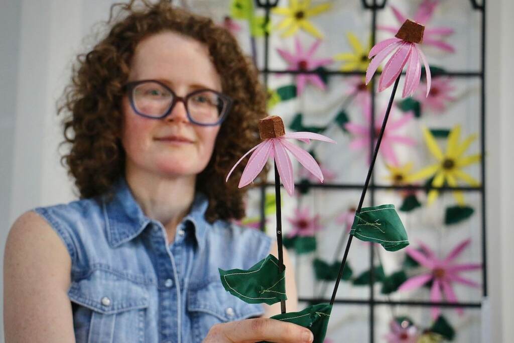 Julie Woodard holds up one of her artworks, a flower made from plastic waste.