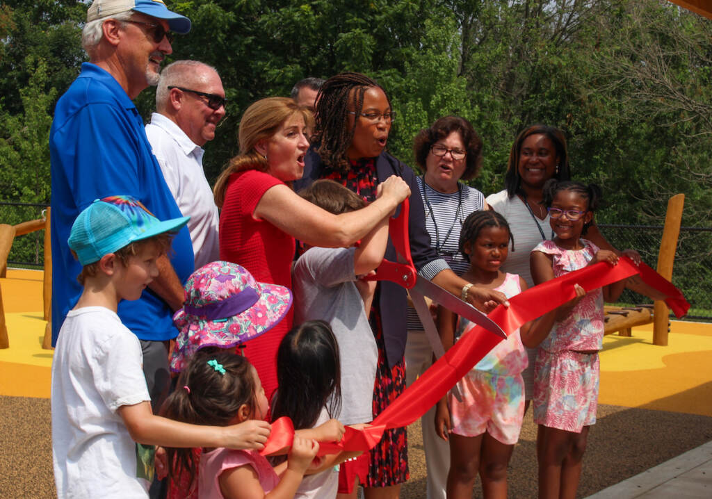 Delaware County officials join children in cutting a ribbon at the new Rose Tree Park Playground.