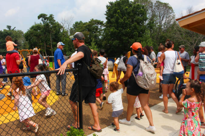Children rush into the entrance of a playground alongside some caregivers.