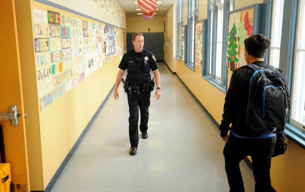 School Shootings-Shield Police officer walks the halls of a high school.