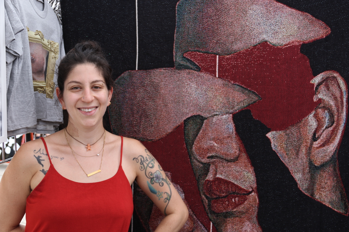 Eva Sturtz has been doing her oil paintings full time since the pandemic began, and converts her work into wares people can buy, like the tapestry she's standing next to