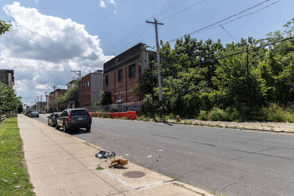 A vacant lot and unused buildings are visible on a street.