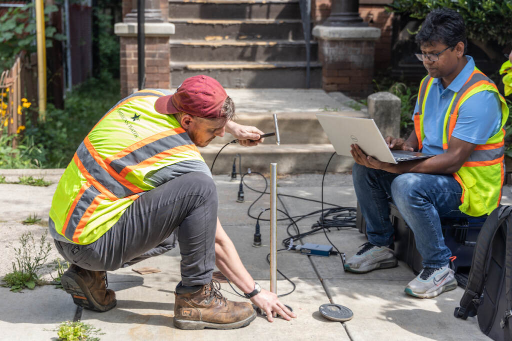 08 17 2023 k paynter everett skipper vp cornwell PWD pilot detect lead pipes-7 Drexel engineers John DeVitis (left) and K I M Iqbal (right) use a hammer, a rod, a computer, and sensors to record vibrations from the pipe below the sidewalk.