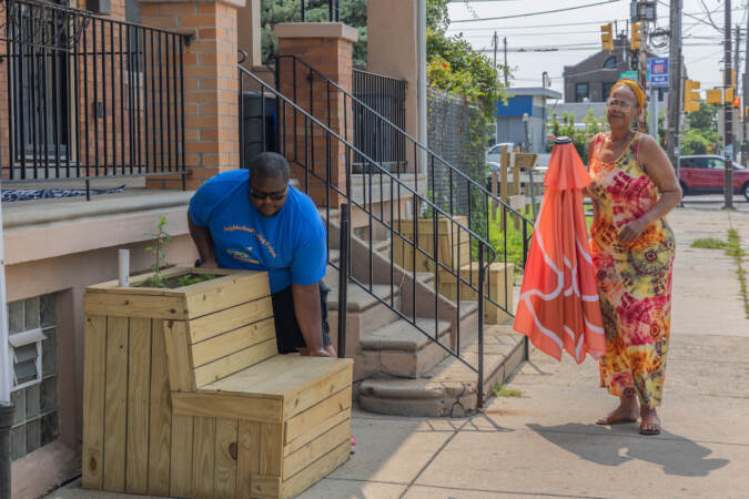 Empowered CDC Inc. climate tracker Jalen Busbee (left) helps 58th Street resident Adrine Wilson (right) position her planter bench outside her home.