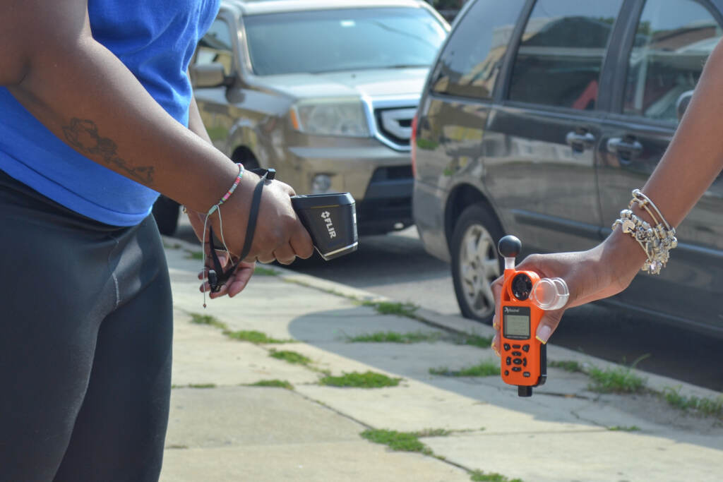 An up-close view of two people holding temperature-taking devices.